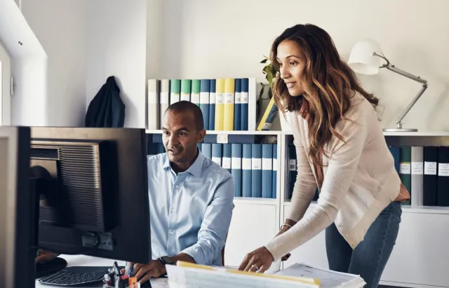 People looking with interest at computer monitor in office